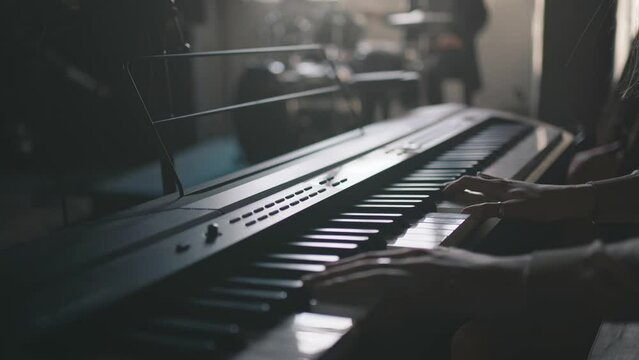 Girl musician play synthesizer and Music band rehearsal at background.