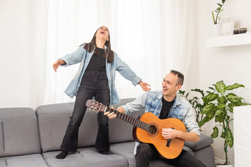 smiling father showing daughter how to play barre chord