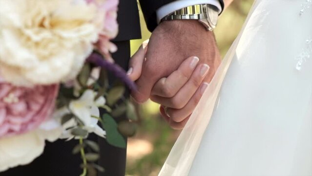 Bride and groom holding hands on a sunny day. Valentine's day concept