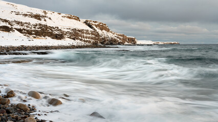 Waves crashing on the shoreline on a cloudy winter day, Northern Norway