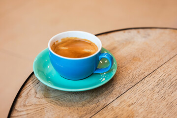 Cup of black coffee on the edge of a wooden table in a cafe, coffee shop with copy space