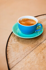 Cup of black coffee on the edge of a wooden table in a cafe, coffee shop with copy space