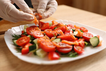Pieces of salmon are added to a vegetable salad. Preparation of vegetable salad