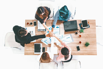 Businessmen and businesswomen joining hands in group meeting at multicultural office room showing...