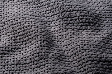 Ciemne szare tło tekstylne, struktura ciepłego, pofałdowanego koca z bliska