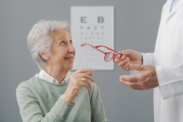 Senior woman having an eye test and trying new glasses - Powered by Adobe