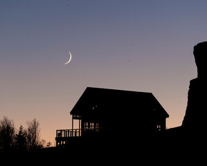 A house with new moon at dusk in Iceland