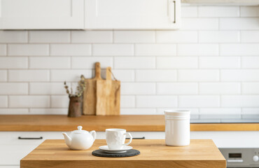 Fototapeta na wymiar Wooden oak table with a cup of tea and a kettle in front of the kitchen with a white brick background.