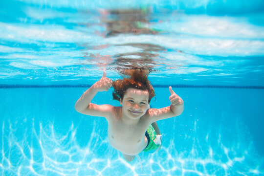 Child splashing in swimming pool. Underwater child swims in pool, healthy child swimming and having fun under water.