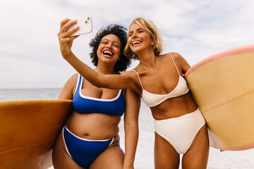 Happy surfing friends taking a selfie on a fun beach vacation