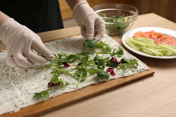 Greens are added to pita bread with cheese. Preparation of a roll with cheese, fish and vegetables