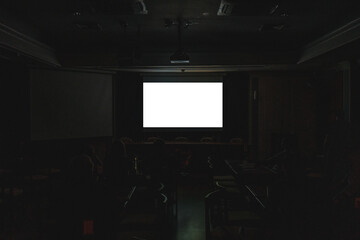 Front view of mockup on blank white cinematic screen with space in dark room and audiences