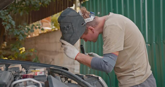Unprofessional car repair. A man repairs a car in an artisanal way.