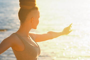 Woman with dreadlocks and shaved temples working out against sea at sunset