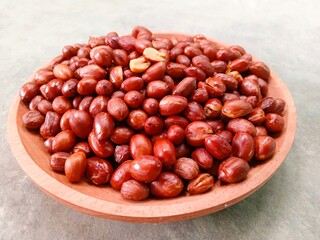 Fried peanuts on wooden plate on gray background. Deep fried peanuts on plate. Close up