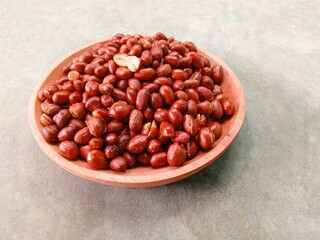 Fried peanuts on wooden plate on gray background. Deep fried peanuts on plate
