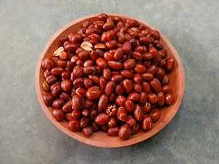 Fried peanuts on wooden plate on gray background. Deep fried peanuts on plate
