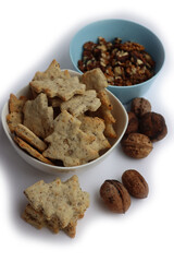 Walnut cookies in shape of a tree in a white bowl with dry walnuts on woooden table 