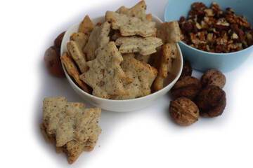 Walnut cookies in shape of a tree in a white bowl with dry walnuts on woooden table 