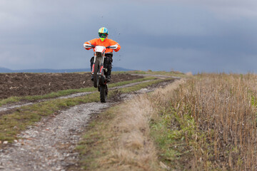 motocross rider wheelie on a rural dirt road with dark blue sky in the background