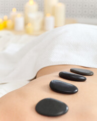 Closeup of young woman receiving hot stone massage