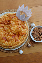 Galette des rois, traditional french cake with almond cream and festive decorations on wooden table. Epiphany cake