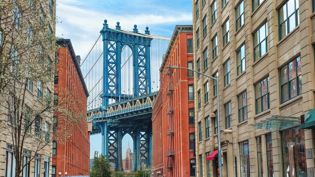  Brooklyn, NYC. Manhattan Bridge between Manhattan and Brooklyn over East River seen from a narrow alley enclosed by two brick buildings.