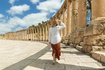 Woman wear a hat enjoys a walk while admiring the columns of the Oval Square in the city of Jerash