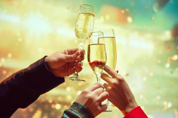 Hands clinking champagne glasses, flutes over light bokeh background. Cheerfully New Years celebration, meeting. Concept of holidays, friendship, fun, joy, leisure, events