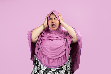 Asian Muslim women with shocked facial expressions and holding her heads Wearing a pink hijab....