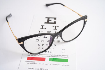Glasses on eye testing exam chart to check eyesight accuracy of reading. - obrazy, fototapety, plakaty