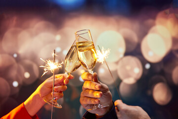 Romantic date night experience service, complete with champagne and sparklers. Two hands holding champagne glasses with sparklers over bokeh lights background. Concept of holidays, celebration, events