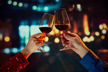 Valentine's Day special promotion at a boutique hotel. Male and female hands clinking glasses with red wine. Anniversary celebration. Romance, Concept of holidays, celebration, events