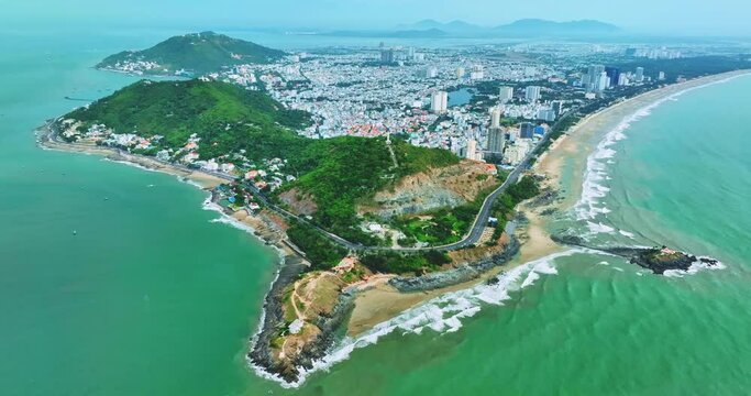 The coastal Vung Tau, Vietnam aerial view with many boats, waves, coastline, streets, coconut trees and Tao Phung mountain in Vietnam.