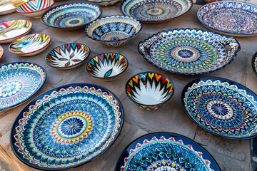 The blue plate is a traditional craft of Uzbekistan. ancient city of Bukhara market of ceramic tableware - obrazy, fototapety, plakaty