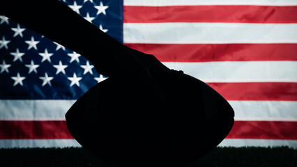 Hand holding Silhouette of American football ball against usa flag