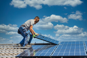 Installing solar photovoltaic panel system. Solar panel technician installing solar panels on roof. Alternative energy ecological concept. - obrazy, fototapety, plakaty