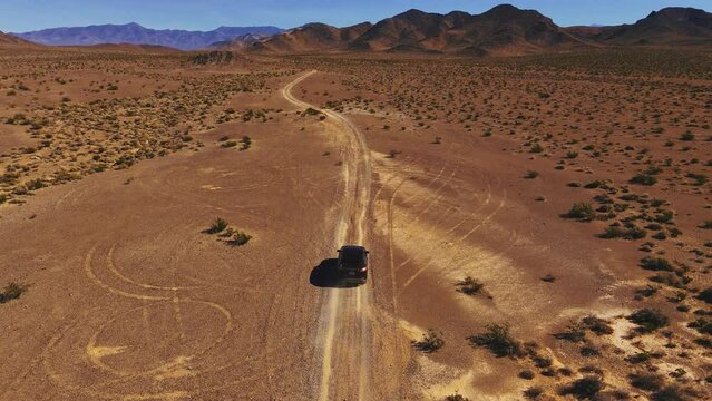Driving a modern car on desert dirt road off-road in Nevada close to Death Valley. Dry hot Wild West America landscape. Aerial drone