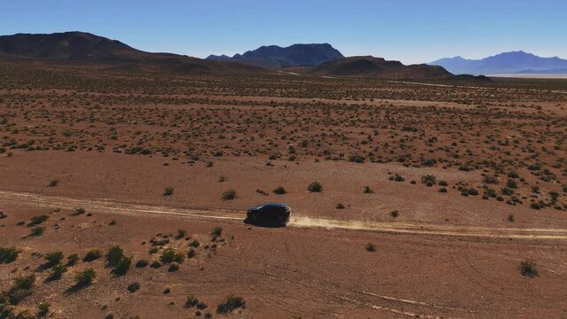Driving a black car on desert dirt road off-road in Nevada close to Death Valley. Dry hot Wild West America landscape. Aerial drone
