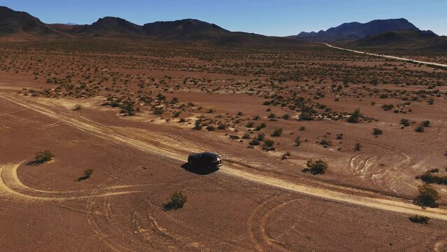 Car driving on desert dirt road off-road in Nevada close to Death Valley. Dry hot Wild West America landscape. Aerial drone