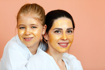 Family spa day. Young beautiful mother and little daughter in bathrobes doing beauty treatment together