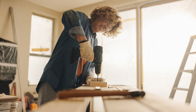 Woman smiling while renovating her kitchen with hand tools - Powered by Adobe