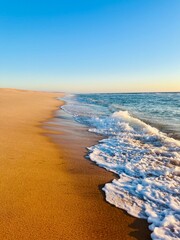 Warm colors of the seascape, sand sea coastline, sea waves on the sand, clear blue sky, no people,...