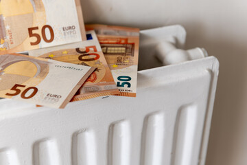 A pile of 50 Euro bank notes on top of a central heating radiator. A European heating utilities...