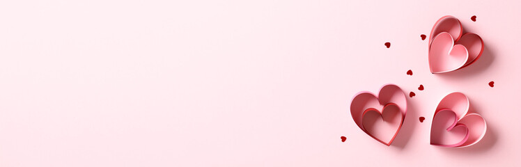 Valentine's Day banner design with copy space. Red paper hearts and confetti on pink background.