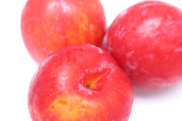 three plums. plums on white background. red colored fruits. fruits with selective focus.