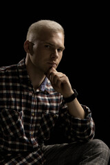 Portrait of an attractive man with blond hair in a checkered shirt on a black background.