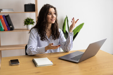 Happy businesswoman gesturing on video call on laptop at home office