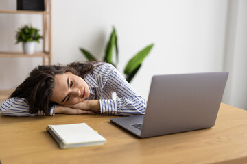 Overworked and tired businesswoman sleeping over a laptop at work in her office