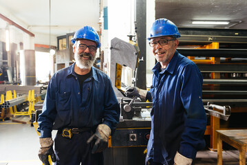 Smiling professional workers standing in factory workshop